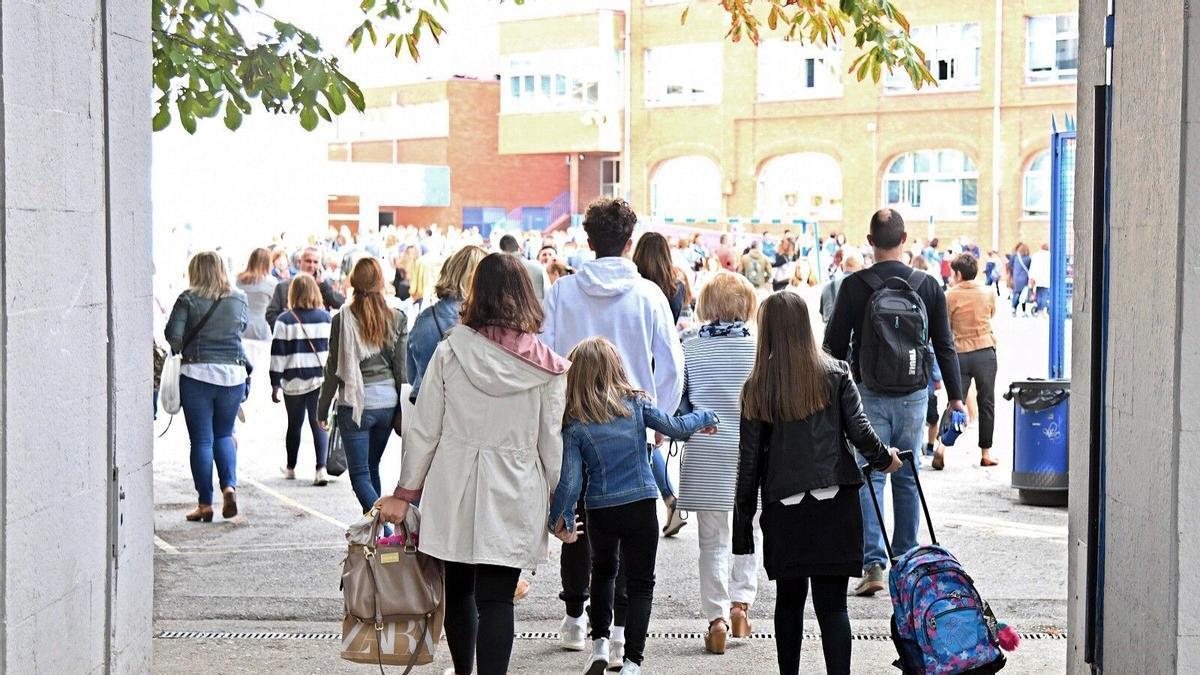 Niños entrando a un colegio junto a sus padres.