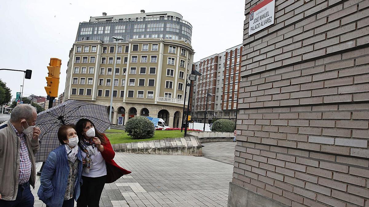 Isabel Palacio Álvarez observa la placa con el nombre de su hermano bajo la mirada de Armando Nosti e Isabel Menéndez. En el círculo, la placa con el nombre del alcalde de Gijón sobre los restos del retirado rótulo de Juan Carlos I. | Ángel González