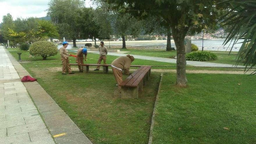 Los alumnos, ayer, reparando los bancos de madera de la alameda del centro. // S. Álvarez