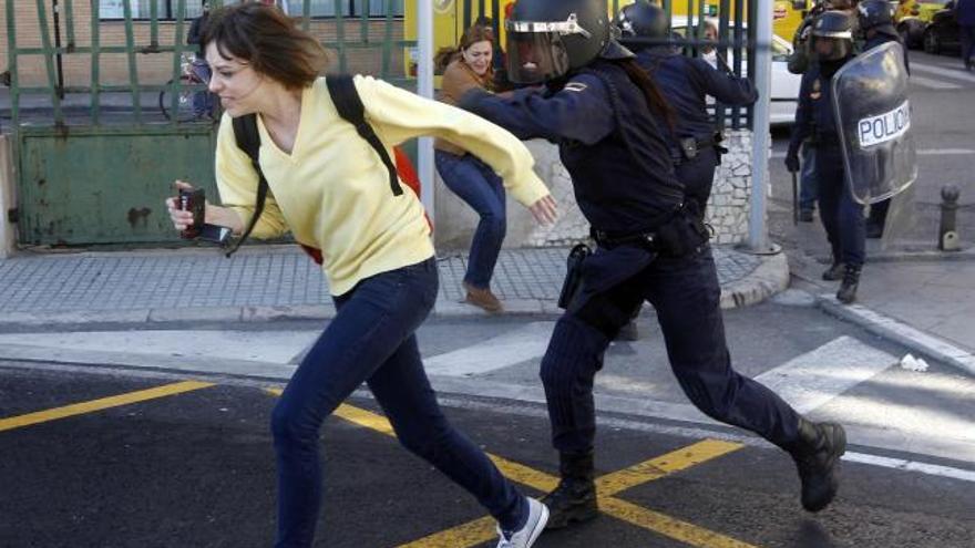 Un policía carga contra una estudiante ante el IES Lluís Vives de Valencia.