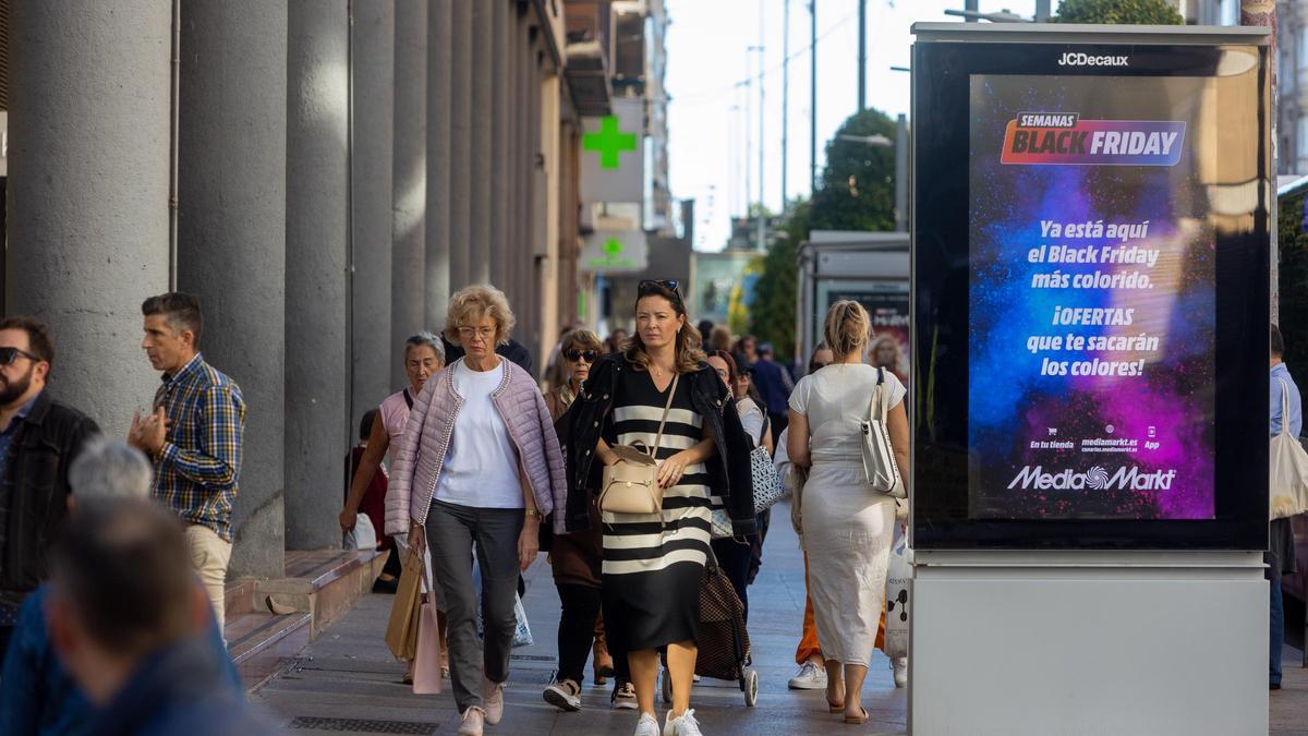 Decenas de personas pasean por Maisonnave, junto a un anuncio del Black Friday.