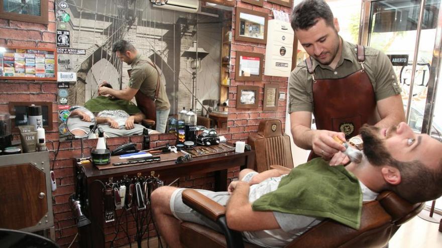 Diego Giménez, brocha en mano, en su barbería de estilo vintage.
