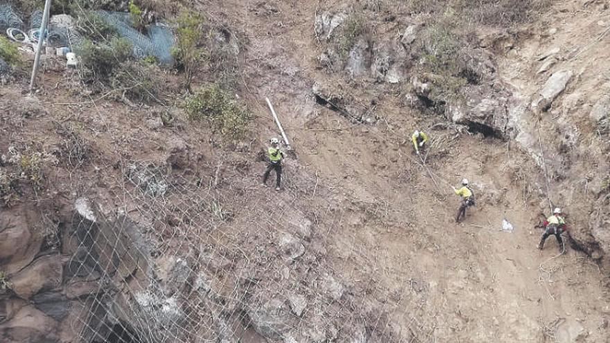 Los operarios trabajan colgados con cuerdas de las rocas.