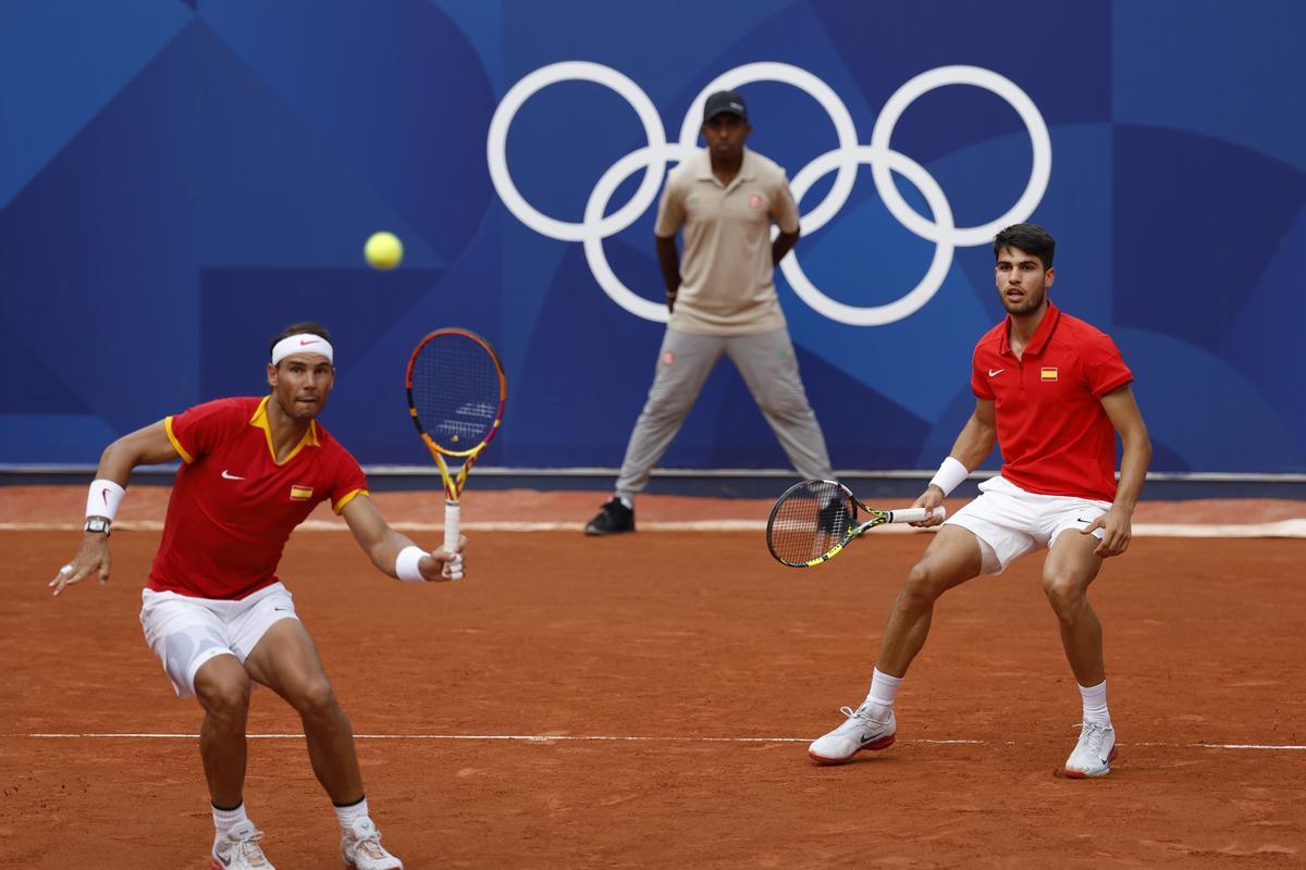 PARÍS, 30/07/2024.- Los tenistas españoles Rafa Nadal (i) y Carlos Alcaraz en acción ante la pareja de Países Bajos compuesta por Wesley Koolhof y Tallon Griekspoor este martes, durante el partido de segunda ronda de dobles masculino de tenis, parte de los Juegos Olímpicos de París 2024, en la capital francesa. EFE/ Juanjo Martín