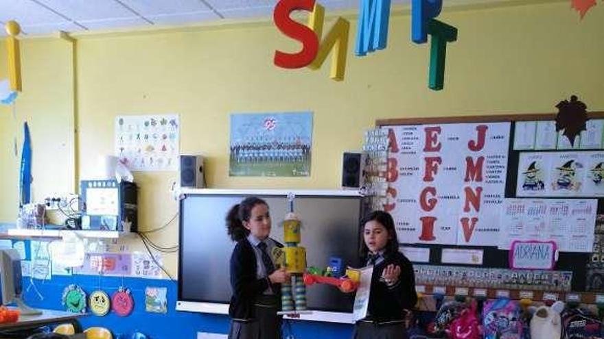 Dos alumnas de quinto de Primaria presentan a Ecolarry a sus compañeros y les explican cómo reciclar. // D. P.