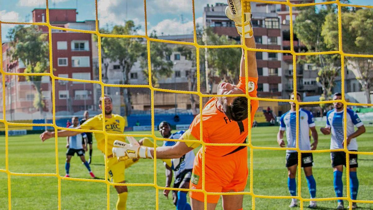 El portero del Hércules Falcón se estira, pero no puede impedir el gol de cabeza del central del Orihuela Lolo Pavón en el minuto 10. | TONY SEVILLA