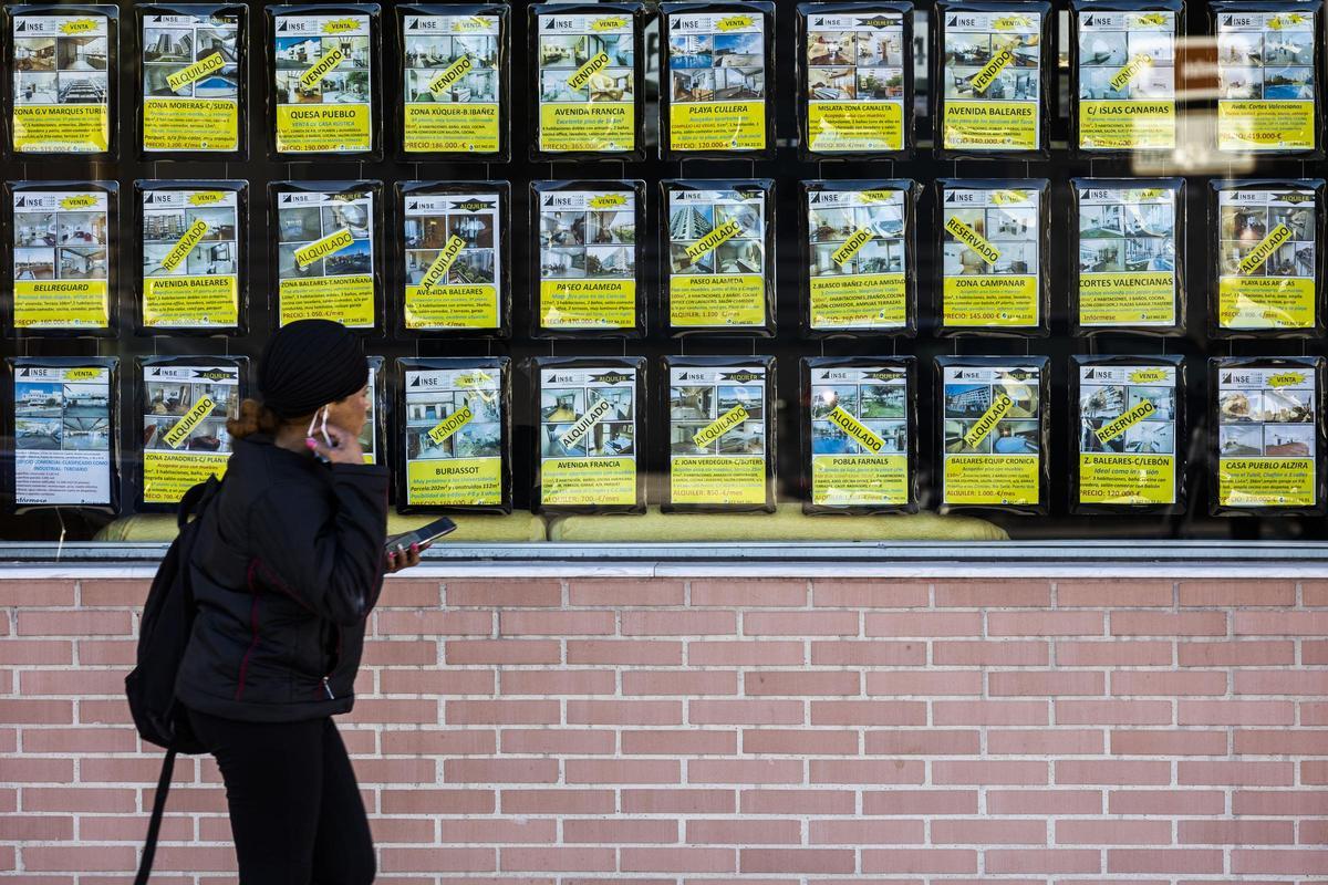 Una joven pasa ante el escaparete de una inmobiliaria en València.