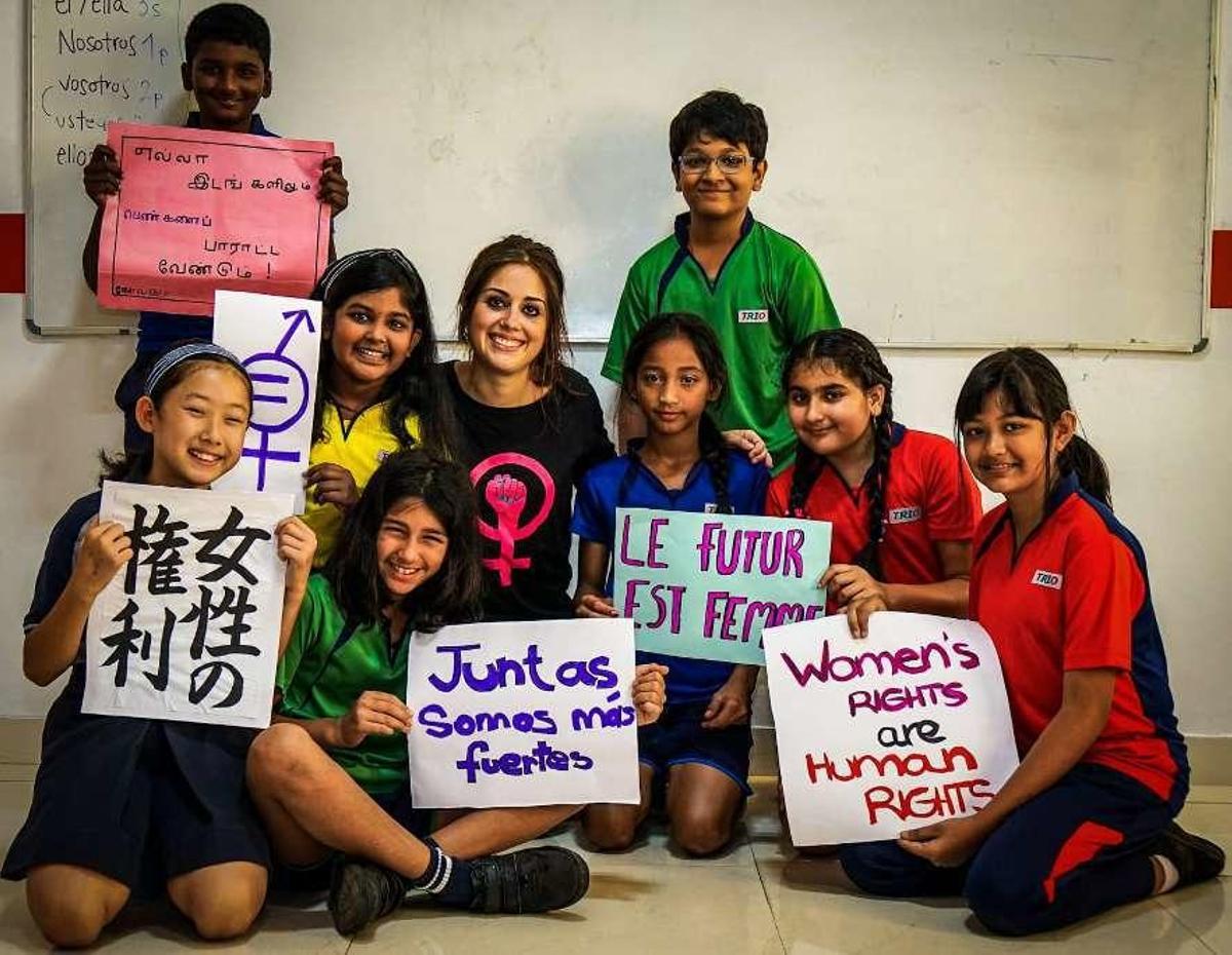 La profesora asturiana Sara Mañanes, en el centro, junto a sus alumnos de Bangalore (India), que muestran mensajes en diferentes idiomas a favor de la lucha feminista.