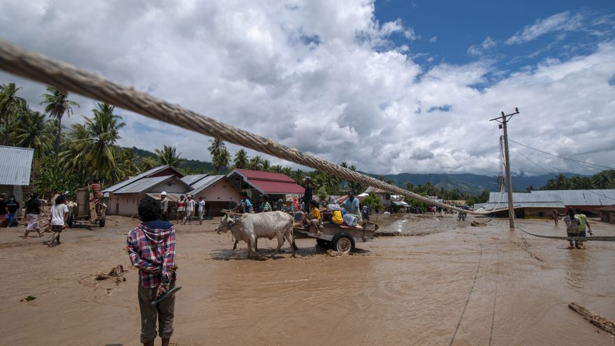 Los residentes transitan a través de un camino fangoso después de inundaciones en la isla de Sumatra.