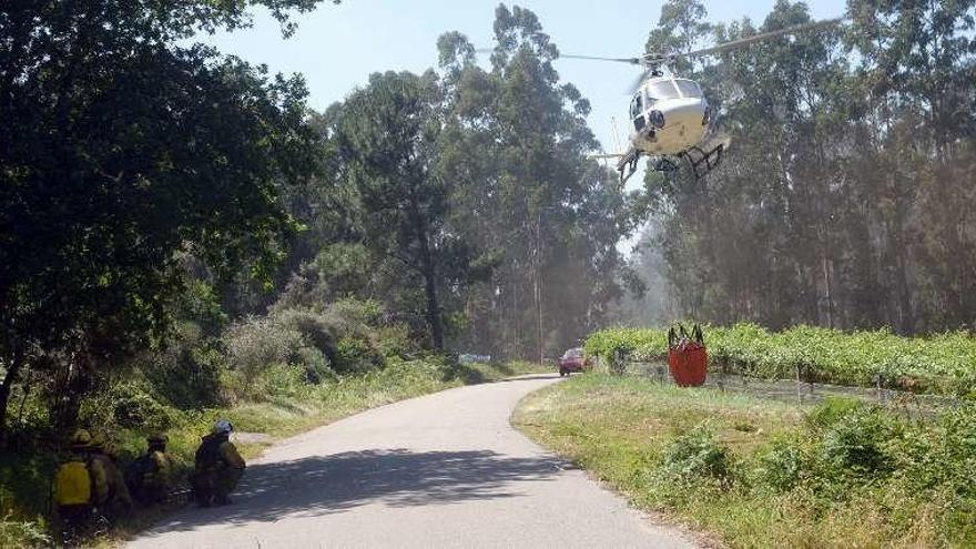 Los bomberos aguardan agazapados a que actúe el helicóptero. // N.P.