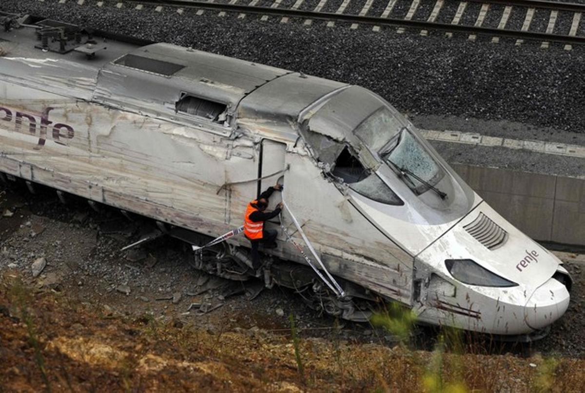 Un operari intenta accedir a la sala de màquines del tren accidentat.