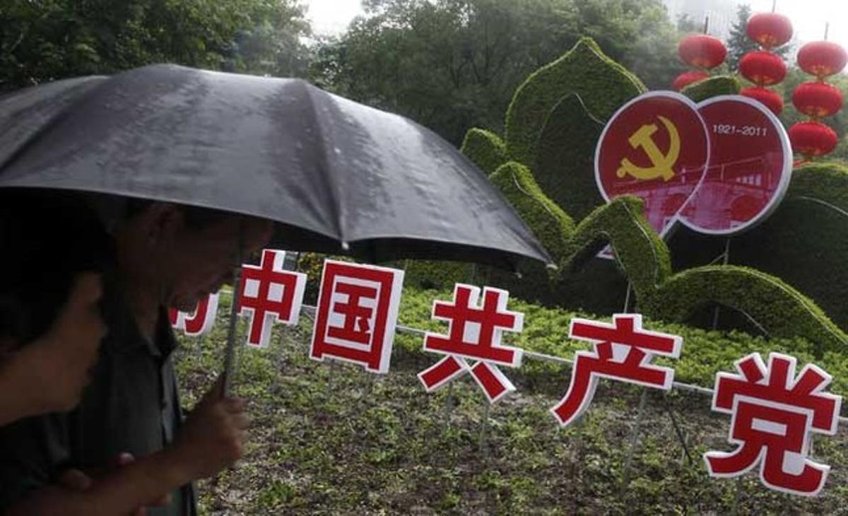 Una parella passa per davant d’un anunci que celebra el pròxim 90è aniversari de la fundació del Partit Comunista de Xina l’1 de juliol, en un jardí de Xangai.