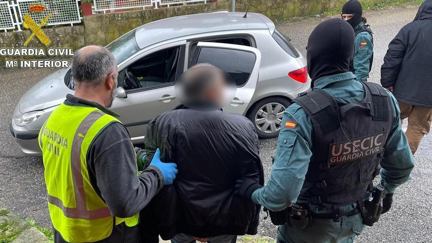 Los agentes llevan detenido a uno de los varones arrestados en la operación.