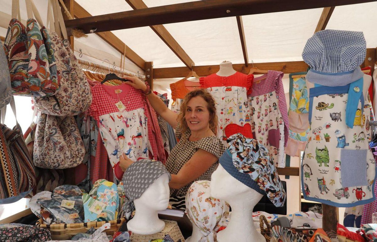 Sheila Gervasoni muestra una de las prendas que vende y, a la derecha, clientas ante un puesto de joyería. | FERNANDO RODRÍGUEZ