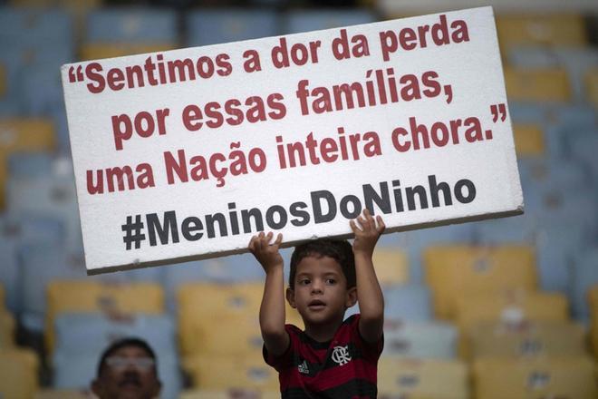 Un joven del Flamengo sostiene un cartel en honor a los 10 jugadores del Flamengo que murieron en un incendio, antes del partido de Taca Guanabara 2019 entre el brasileño Flamengo y el brasileño Fluminense en el estadio Maracaná en Río de Janeiro.
