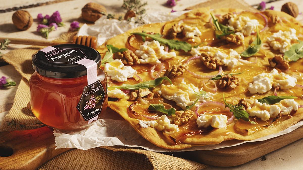 La miel de tomillo Alemany añade un contrapunto balsámico y ligeramente herbal a una coca salada con queso y frutos secos, ejemplo del giro gastronómico del producto.