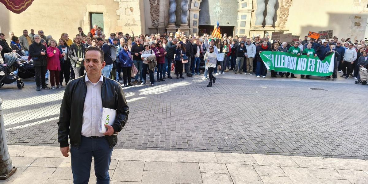 El portavoz de Vox, Josué Brito (en primer plano) a su salida del ayuntamiento y con los manifestantes en favor del valenciano realizando la protesta.