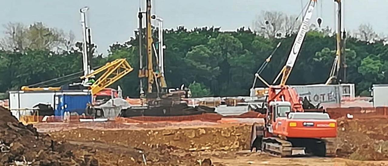 Sobre estas líneas, trabajos de cimentación para la gran nave. A la izquierda, un guarda, ayer, en su ronda. Debajo, material y maquinaria en la zona | P. T.