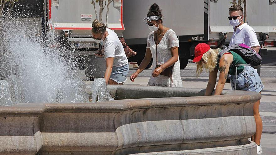 Un grupo de jóvenes se refresca en la fuente de la Plaza de la Virgen ayer.