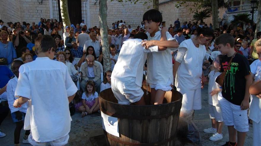 Dos muchachos se apresuran a pisar su porción de uvas ante una plaza repleta de espectadores.