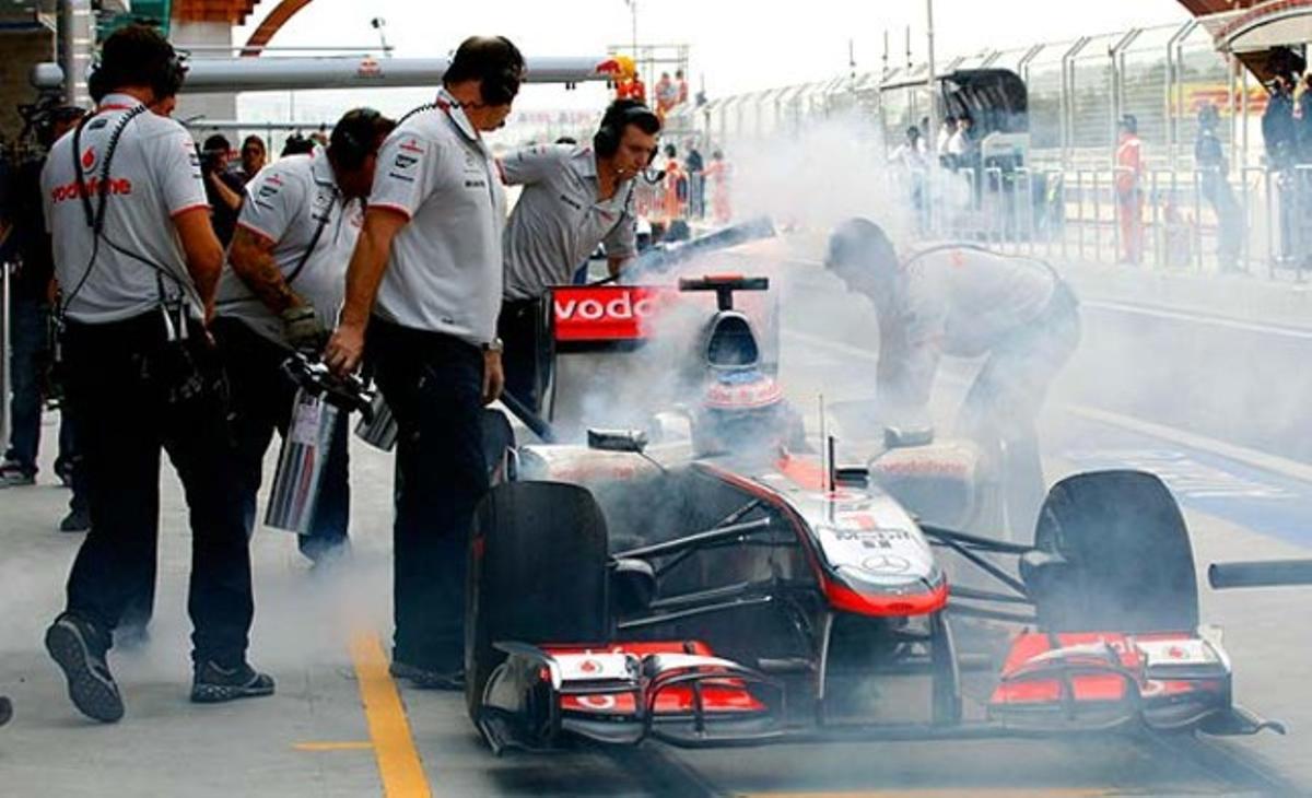 Miembros de McLaren rocían con unos extintores las ruedas del coche de Jenson Button, durante la preparación en el circuito internacional de Corea del Sur.