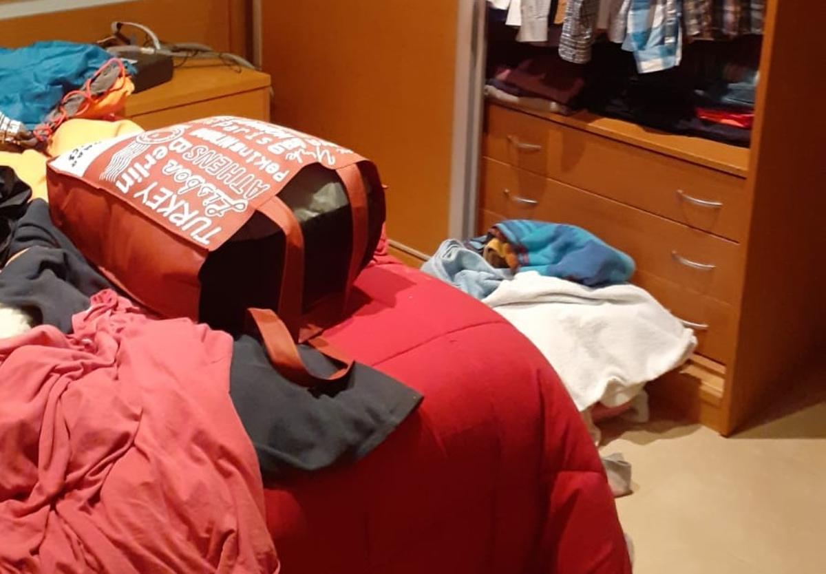 Dormitorio del chalé revuelto, con la ropa por el suelo.