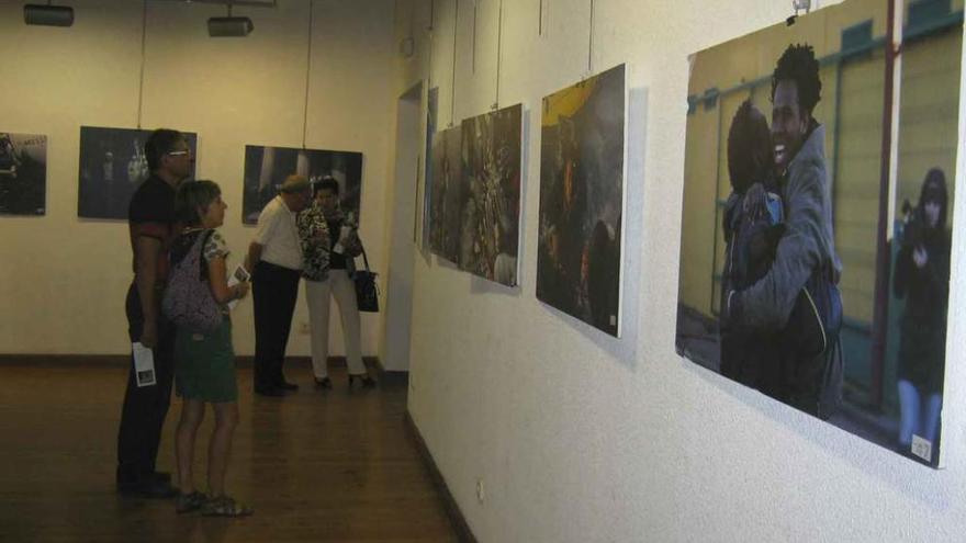 Varias personas admiran las fotografías de la exposición que acoge la Casa Municipal de Cultura.