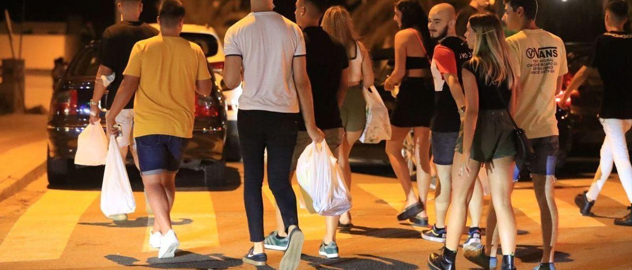 Jóvenes con bolsas de bebidas para hacer botellón.