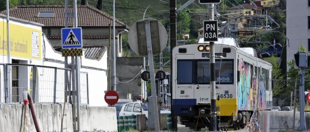 Un tren de Feve circula por el entorno donde se realizan las obras del soterramiento de la línea, en Langreo.