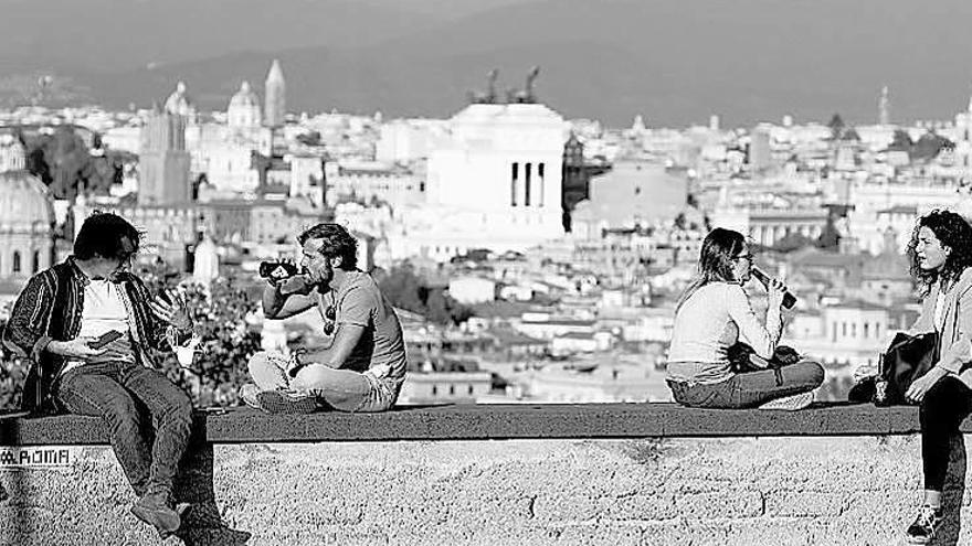 Jóvenes beben al aire libre en un espacio público de Roma.