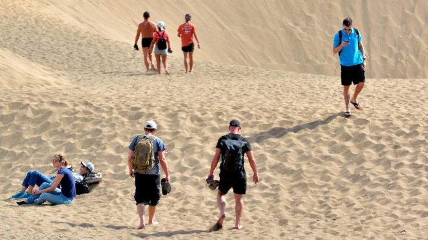 Varios turistas caminan por las Dunas de Maspalomas.