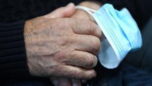 Archivo - Una persona mayor con una mascarilla entre sus manos