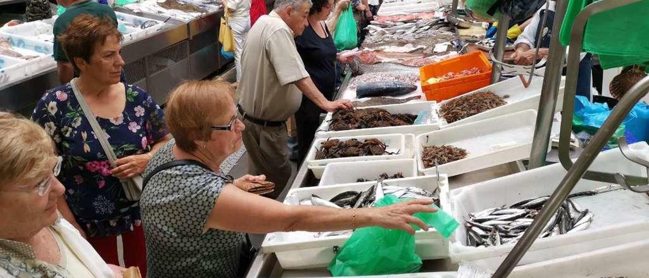 Varios clientes ante las bancadas de pescado y marisco del Mercado. // Santos Álvarez