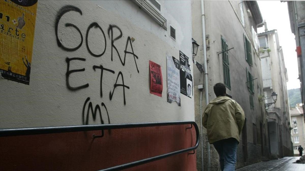 Una persona junto a un graffiti proetarra.