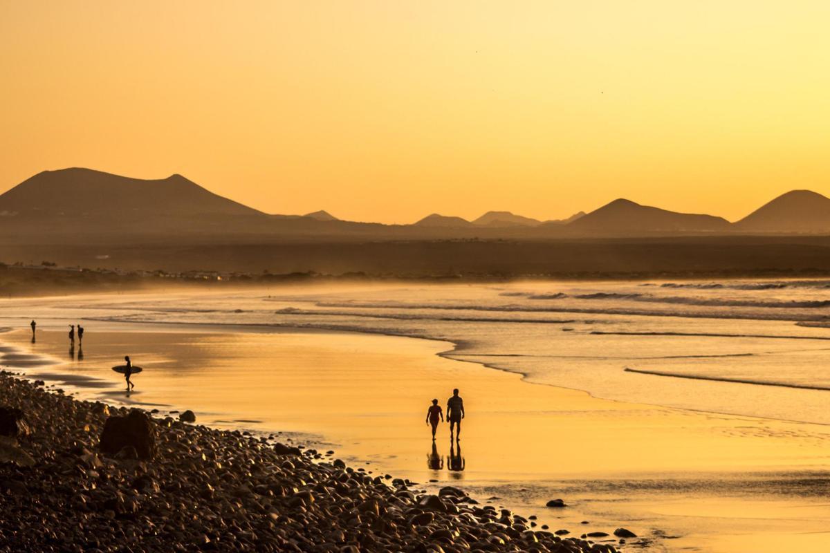 Uno de los lugares más icónicos de las Islas Canarias para ver atardecer es la playa de Famara, en Lanzarote: una paradisiaca extensión de arena fina coronada por una montaña en uno de sus extremos.