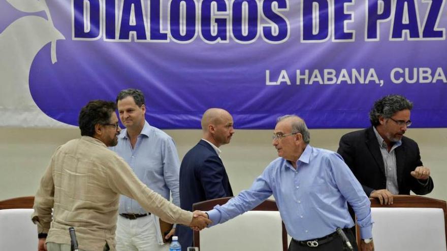 Los negociadores De la Calle (Gobierno) y Márquez (FARC), a la izquierda, se estrechan la mano tras la firma de los protocolos.