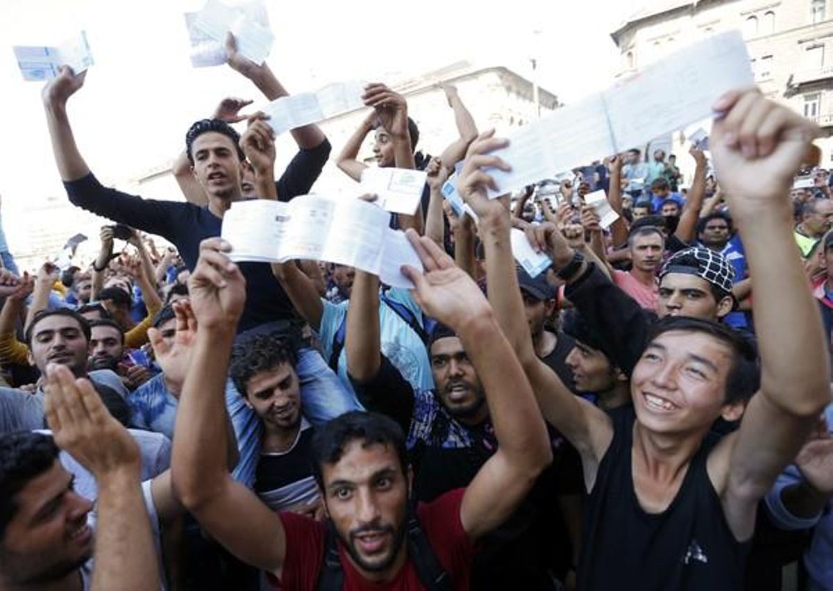 Los refugiados muestran sus billetes de tren con indignación mientras esperan que los trenes vuelvan a circular en la estación de Keleti.