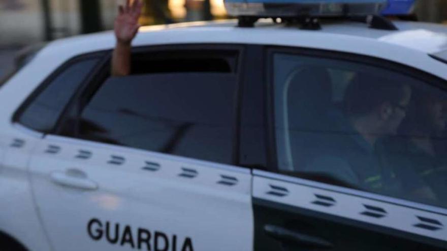 El detenido saca la mano por la ventanilla del coche policial cuando es trasladado a Sanxenxo. // Muñiz