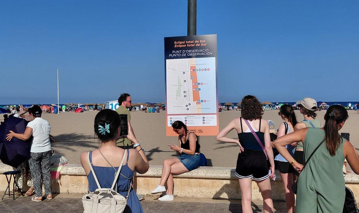 Personas frente a un cartel que indica el eclipse, esta tarde.