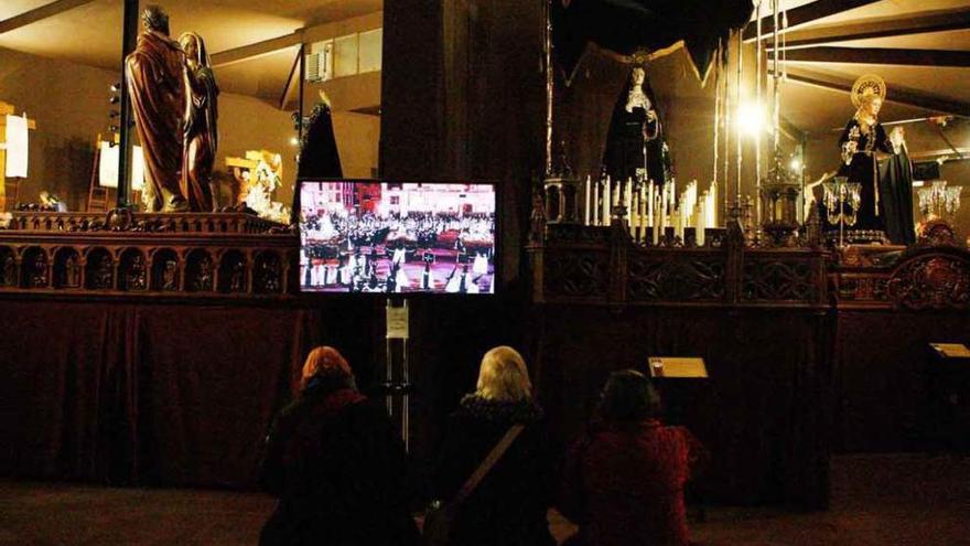 Tres visitantes observan un vídeo en el Museo de Semana Santa después de su último lavado de cara.