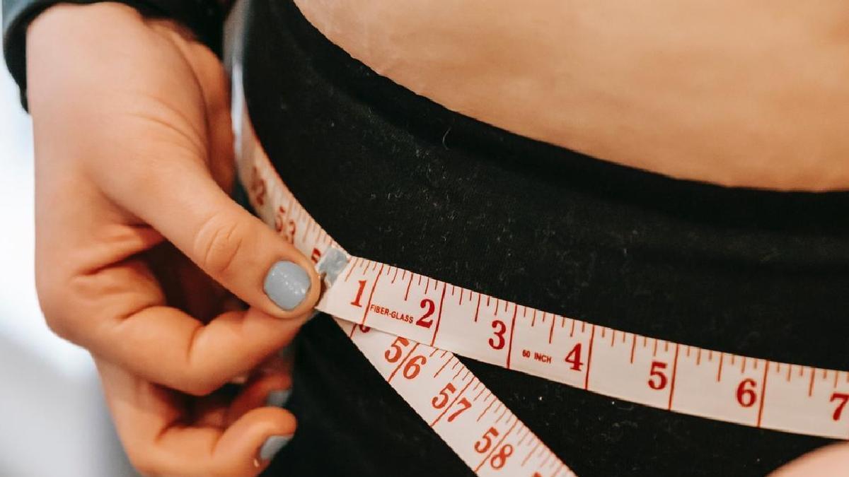 Una mujer se mide la cintura.
