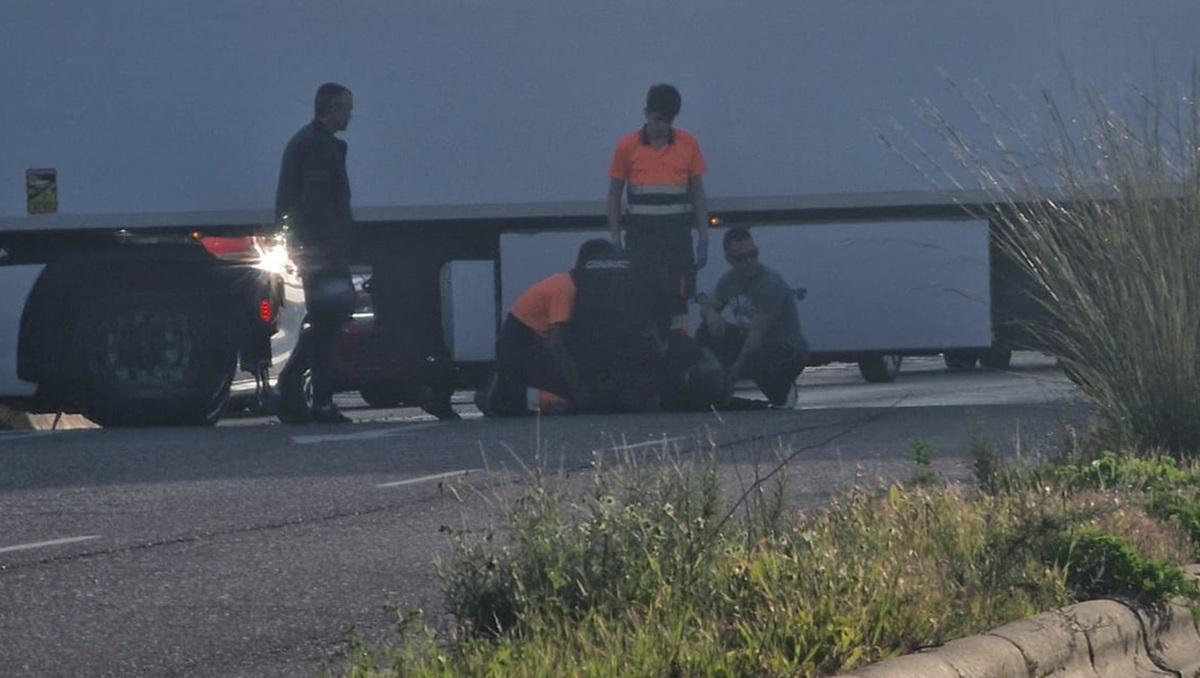 Sanitarios atienden al motorista herido, en el suelo.