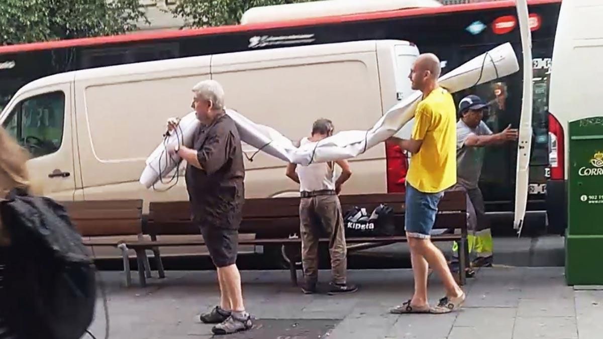 Unos hombres sacan de una furgoneta la pancarta supuestamente contraria al Rey.