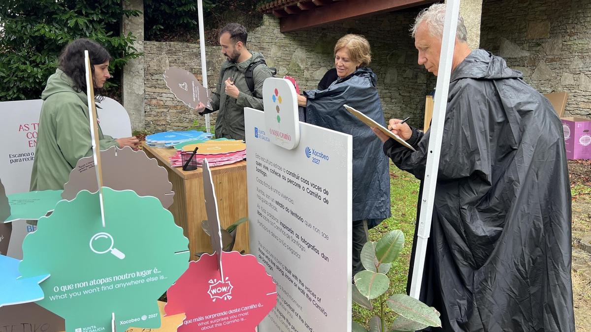 Un grupo de peregrinos plasmando sus impresiones sobre el Camino en la instalación del proyecto O noso Camiño, en Mesía.
