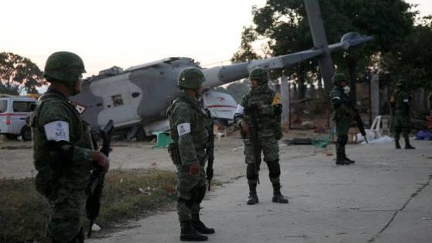 Diversos soldats custodien les restes de l&#039;helicòpter accidentat.