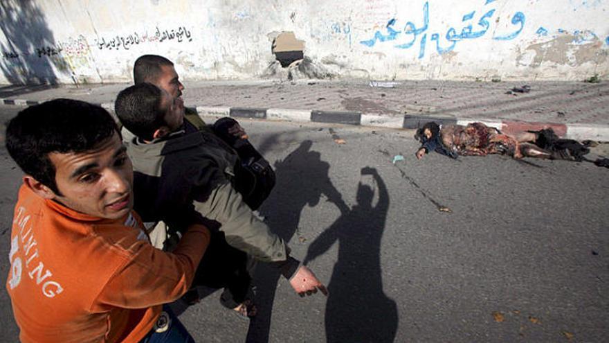 Dos homes passen pel costat d&#039;un cadàver mentre porten un presumpte membre de Hamas ferit.