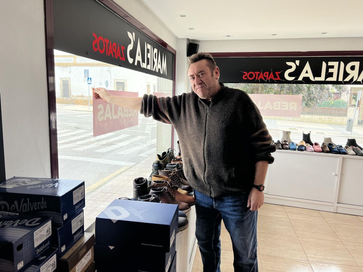 Luis, propietario de la zapatería Mariela's, colocando los carteles de rebajas.