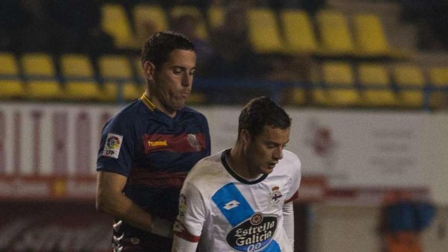 Riera protege el balón, presionado por un defensor local.