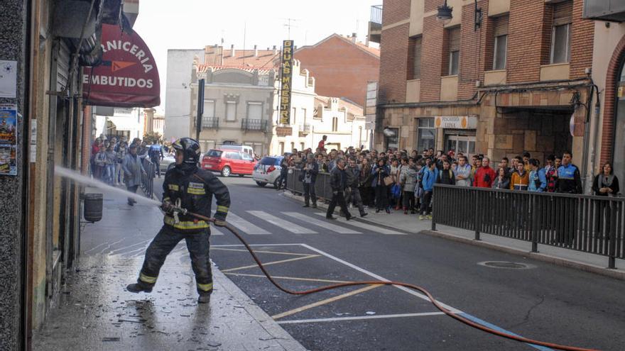 Un bombero sofoca el fuego. En segundo plano, el anciano propietario del edificio incendiado