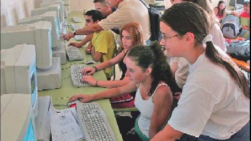 Alumnos de un instituto de Alicante comparten ordenadores en la biblioteca donde están instalados los terminales